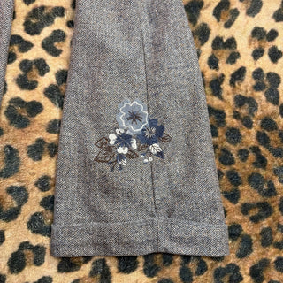 Gray textured fabric with floral embroidery on a leopard print background