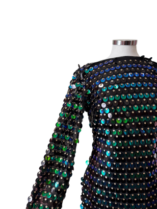 Mannequin wearing a black sequin dress with colorful beads against a pink curtain.