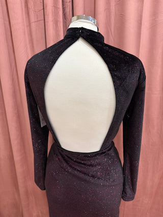 Black long-sleeve dress with open back on a mannequin against a pink curtain background