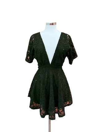 Black lace dress on a mannequin against a pink curtain background