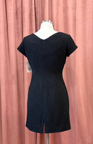 Black dress on a mannequin against a pink curtain background