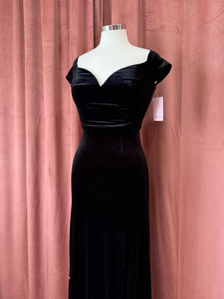 Black evening gown on a mannequin against a pink curtain background